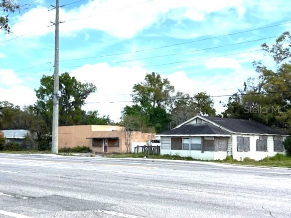A street-level view shows a white house with boarded-up windows next to a tan building — 980 BERKLEY ROAD, AUBURNDALE, FL