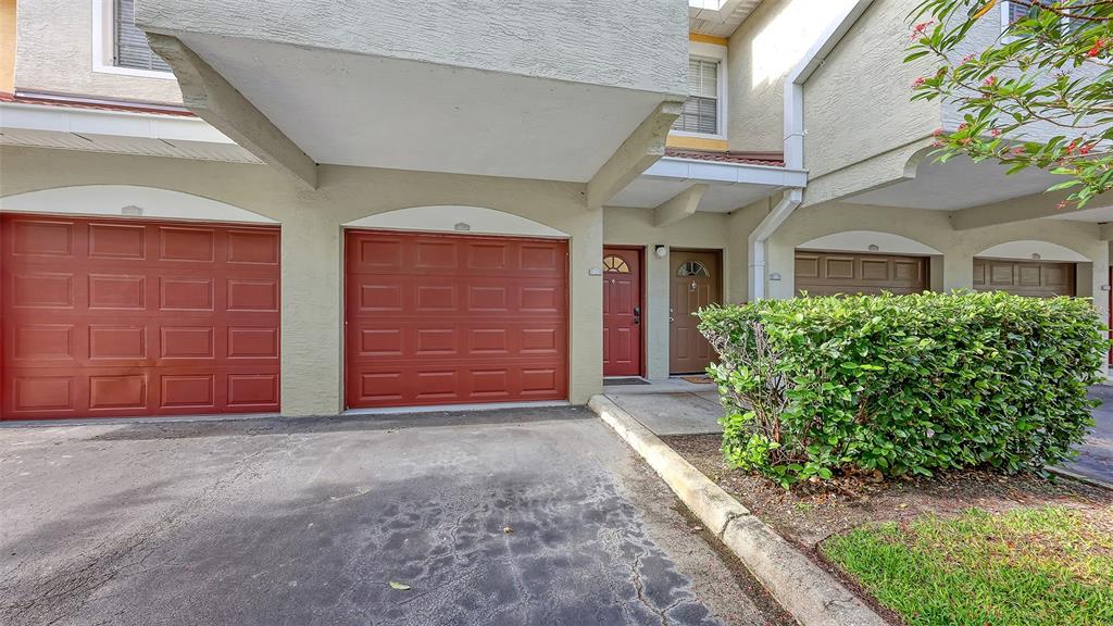 The exterior of a multi-unit residential building features two red garage doors and two entryways — 5001 BARALDI CIRCLE UNIT 22-202, SARASOTA, FL