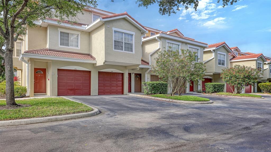A row of multi-story townhomes with red garage doors and tile roofs under a blue sky — 5001 BARALDI CIRCLE UNIT 22-202, SARASOTA, FL
