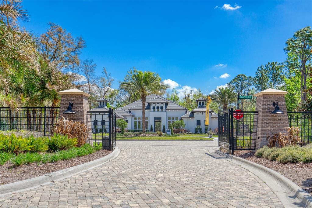 A gated entrance with brick pillars leads to a large house with a paved driveway — 1805 ADRIAN CREEK BOULEVARD, PORT ORANGE, FL