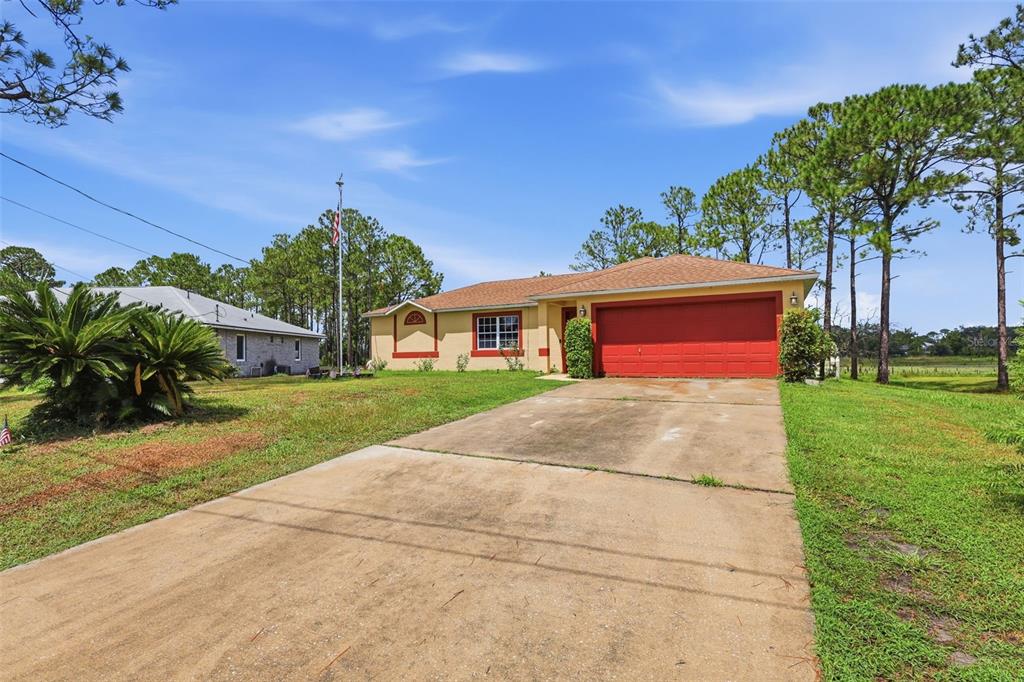 A single-story house with a tan exterior, a red garage door, and a concrete driveway — 2772 PELHAM CIRCLE, DELTONA, FL