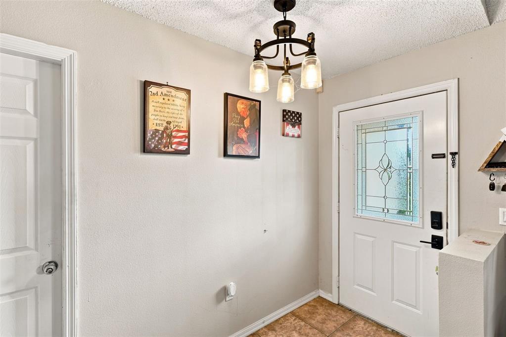 An entryway features a white door with a glass insert, tiled flooring, and wall decor — 2772 PELHAM CIRCLE, DELTONA, FL