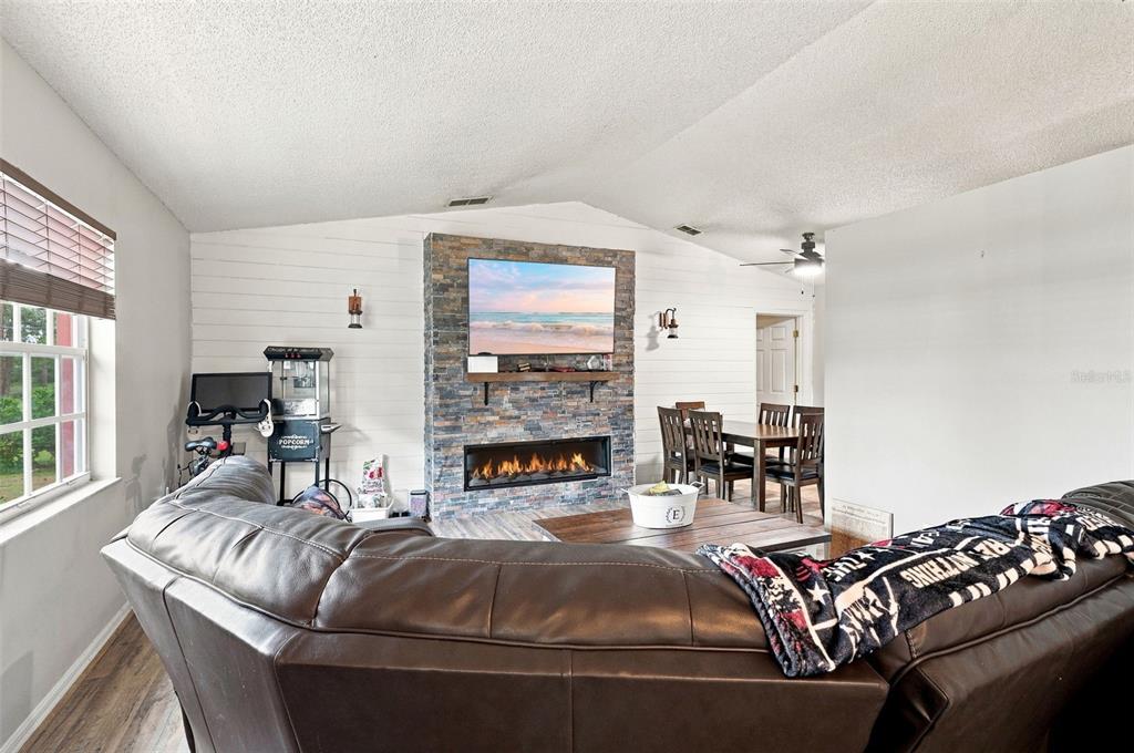 A living room features a stone fireplace, wall-mounted television, and a large brown leather sofa — 2772 PELHAM CIRCLE, DELTONA, FL