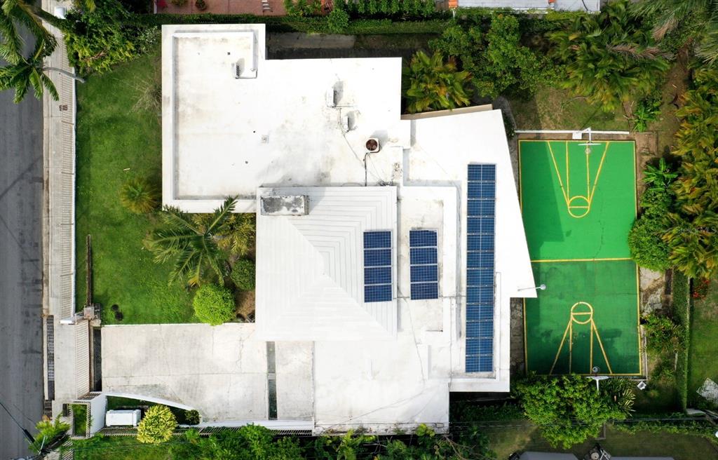 An aerial view shows a house with a white roof, solar panels, and a basketball court — . J STREET UNIT 3, GUAYNABO, PR