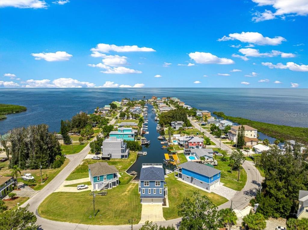 An aerial view of a blue multi-story house with a garage at sunset — 6812 DRIFTWOOD DRIVE, HUDSON, FL