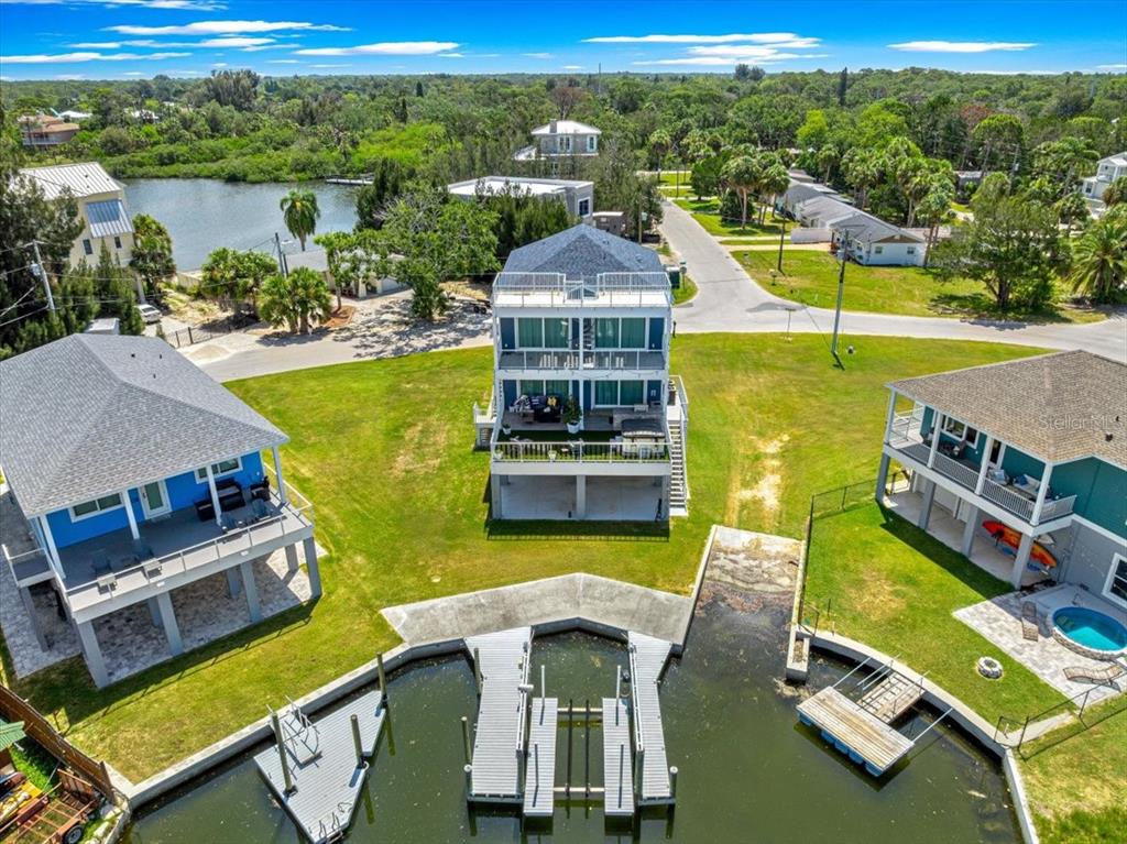 An elevated three-story house features multiple balconies, a rooftop deck, and a ground-level patio area — 6812 DRIFTWOOD DRIVE, HUDSON, FL
