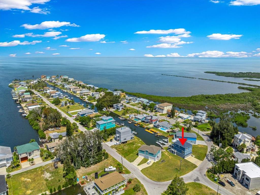 An aerial view shows three elevated waterfront houses with private docks along a canal — 6812 DRIFTWOOD DRIVE, HUDSON, FL