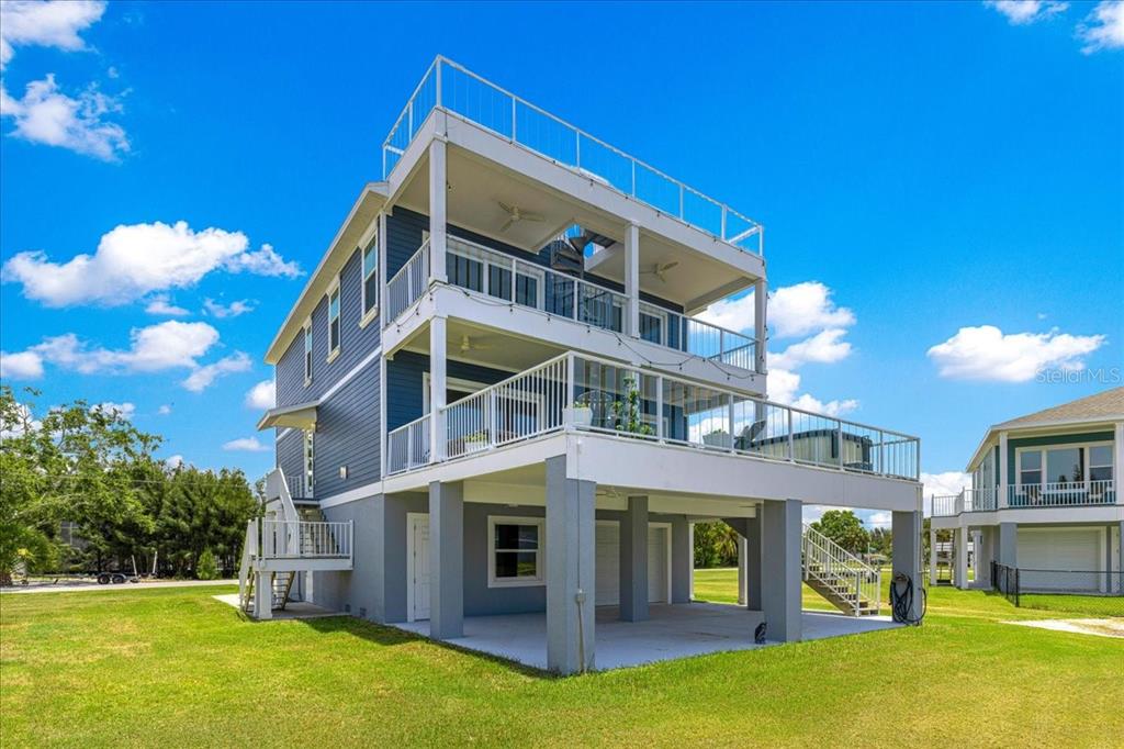 An aerial view shows a blue house with a red arrow pointing to its roof — 6812 DRIFTWOOD DRIVE, HUDSON, FL