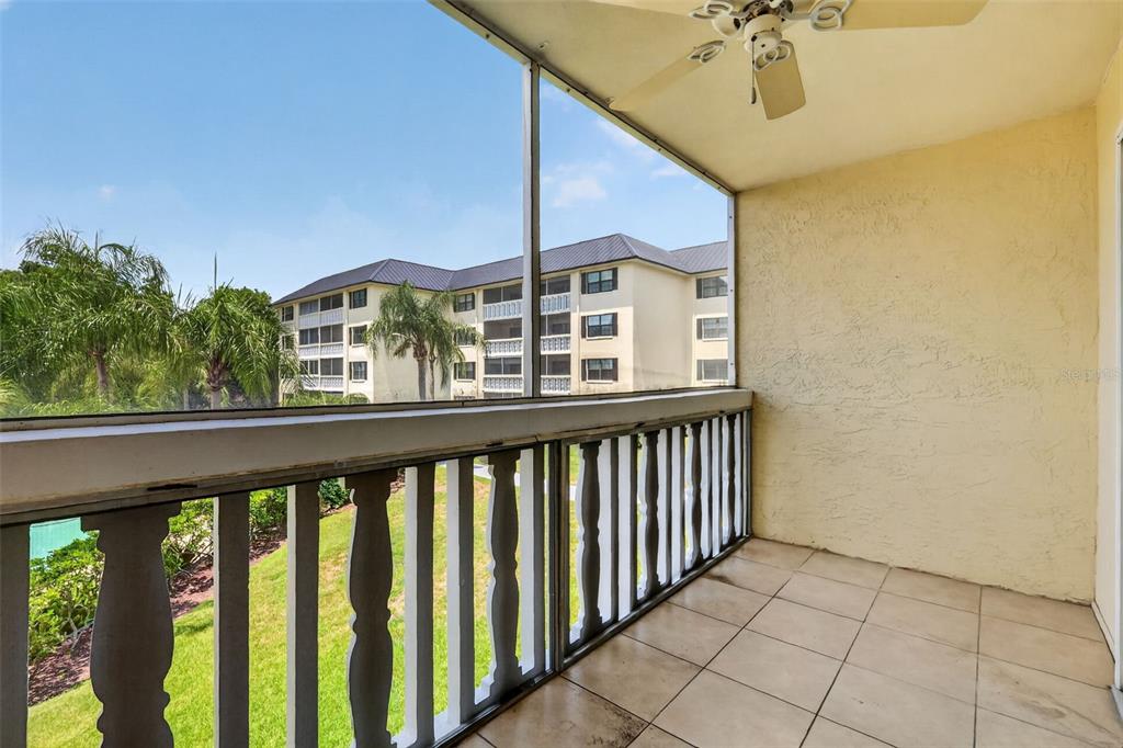 A screened-in balcony with tiled flooring, a ceiling fan, and a view of another building — 101 N GRANDVIEW STREET UNIT 203, MOUNT DORA, FL