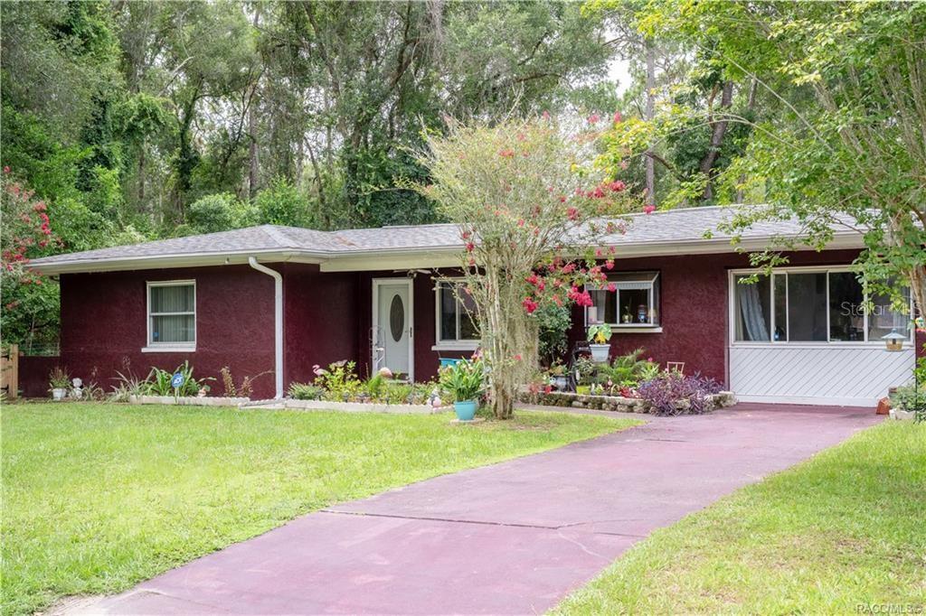 A single-story house with dark red stucco siding, a white front door, and a driveway — 6046 E LORING LANE, INVERNESS, FL