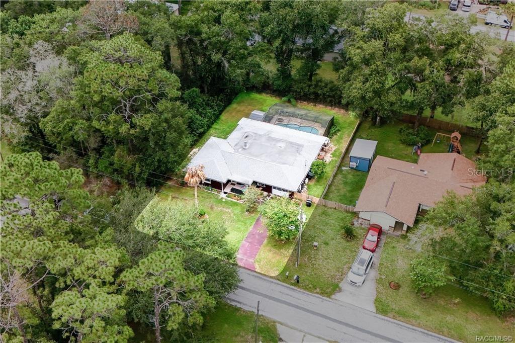 An aerial view shows a single-story house with a pool enclosure and a large yard — 6046 E LORING LANE, INVERNESS, FL