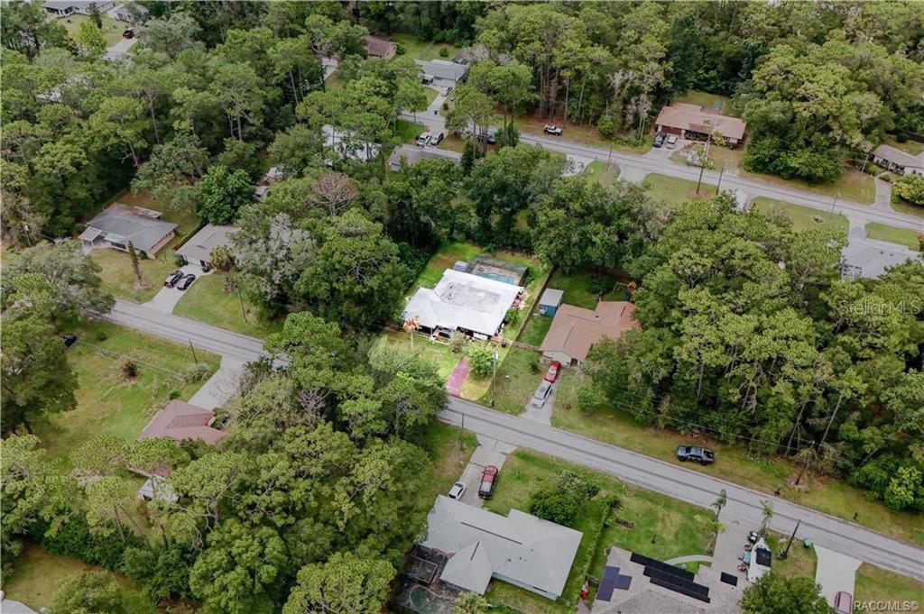 An aerial view shows a residential neighborhood with houses, driveways, and dense surrounding trees — 6046 E LORING LANE, INVERNESS, FL