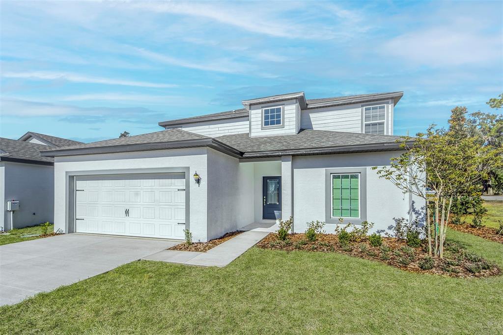 A two-story house with a white stucco exterior, a two-car garage, and a front lawn — 13340 TULA LOOP, ASTATULA, FL