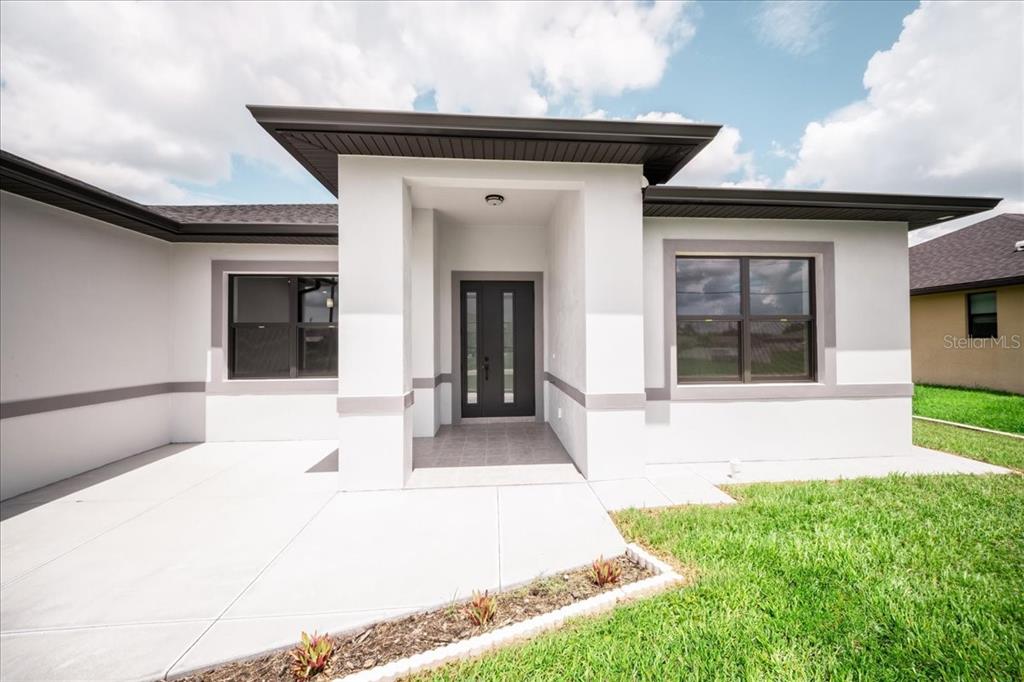 A modern single-story house with a two-car garage and a concrete driveway at sunset — 12060 MARGARITA AVENUE, NORTH PORT, FL