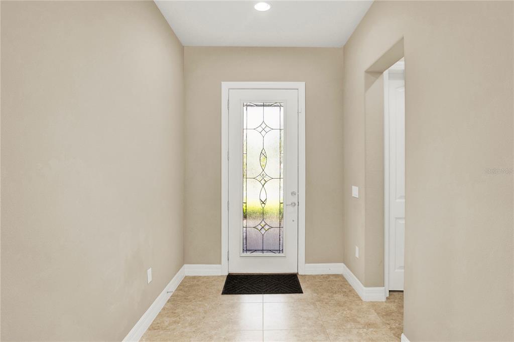 A bright entryway features beige walls, tile flooring, and a white door with decorative glass — 11340 LEMON LAKE BOULEVARD, ORLANDO, FL