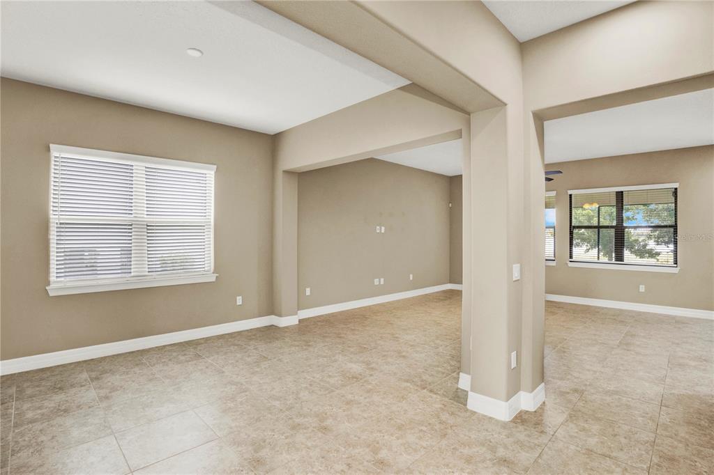 An interior view of an open-concept living area with beige walls and light-colored tile flooring — 11340 LEMON LAKE BOULEVARD, ORLANDO, FL