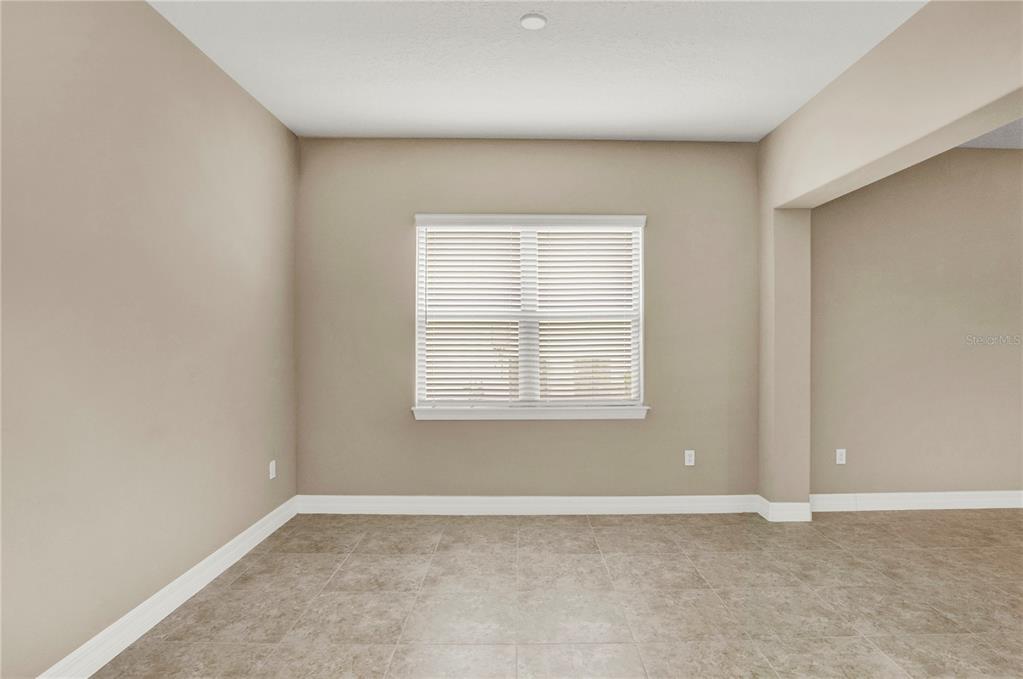 An empty room features beige walls, white trim, and light-colored square floor tiles — 11340 LEMON LAKE BOULEVARD, ORLANDO, FL