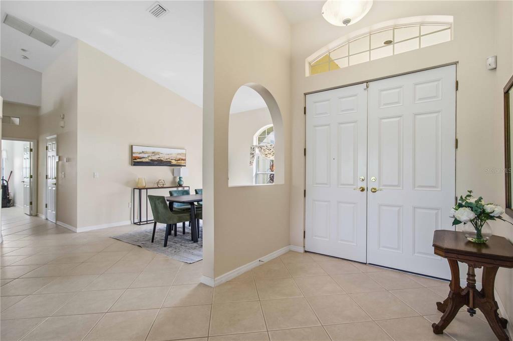 A bright entryway with tile flooring, a double front door, and an arched wall opening — 9215 63RD COURT E, PARRISH, FL