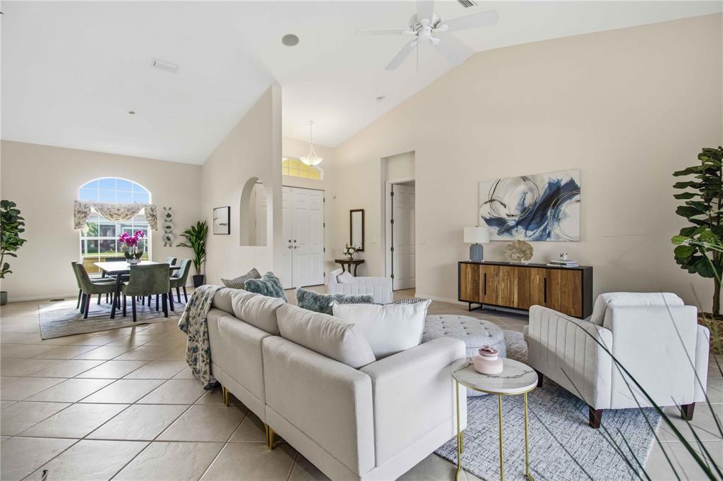 A living room with a vaulted ceiling, beige tile floors, and a white double-door entrance — 9215 63RD COURT E, PARRISH, FL