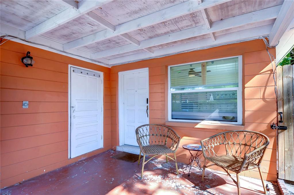 A covered porch with orange siding, two wicker chairs, and two white doors — 4944 5TH AVENUE N UNIT B, ST PETERSBURG, FL
