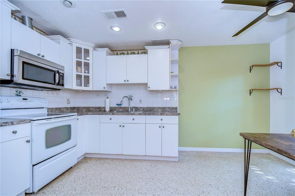 A kitchen with white cabinets, a white stove, a green accent wall, and speckled flooring — 4944 5TH AVENUE N UNIT B, ST PETERSBURG, FL