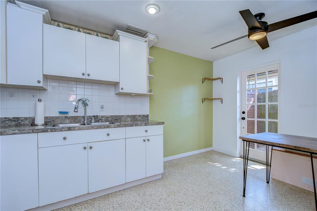 A kitchen features white cabinets, a granite countertop, a green accent wall, and a door — 4944 5TH AVENUE N UNIT B, ST PETERSBURG, FL
