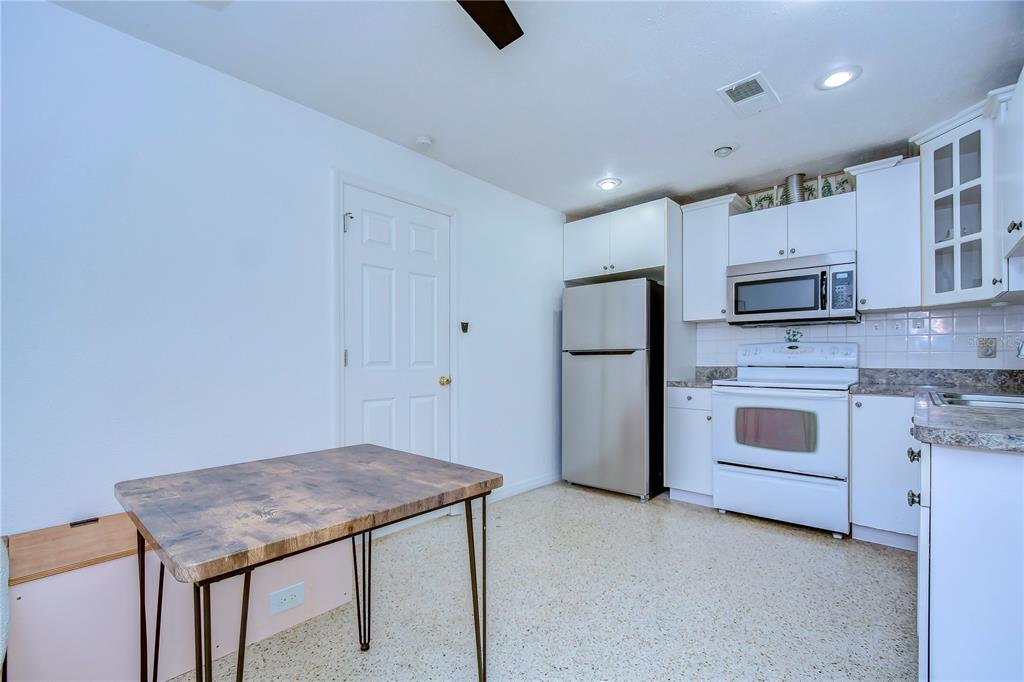 A kitchen features white cabinets, stainless steel appliances, a speckled floor, and a small dining table — 4944 5TH AVENUE N UNIT B, ST PETERSBURG, FL