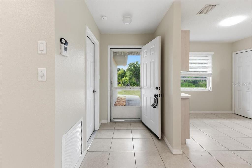 An entryway with tiled floors leads to an open front door showing an outdoor view — 9216 ANITA AVENUE UNIT A, ENGLEWOOD, FL