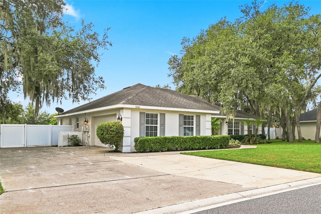 A single-story house with a white exterior, gray shutters, and a concrete driveway — 1845 FARRINGTON DRIVE, LAKELAND, FL