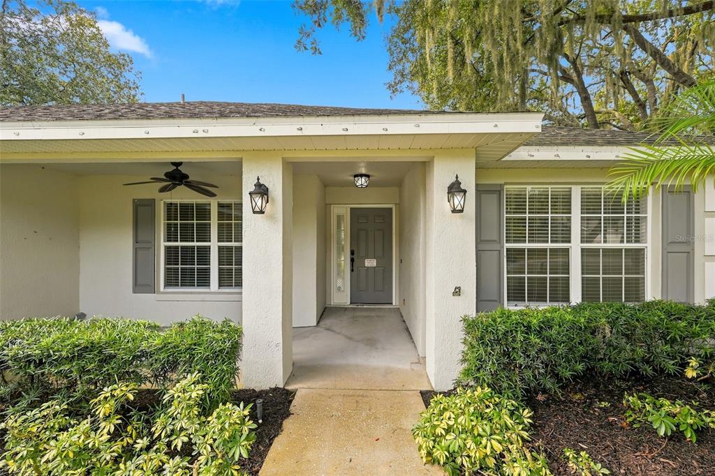 The front exterior of a house features a covered entryway, a gray door, and landscaping — 1845 FARRINGTON DRIVE, LAKELAND, FL