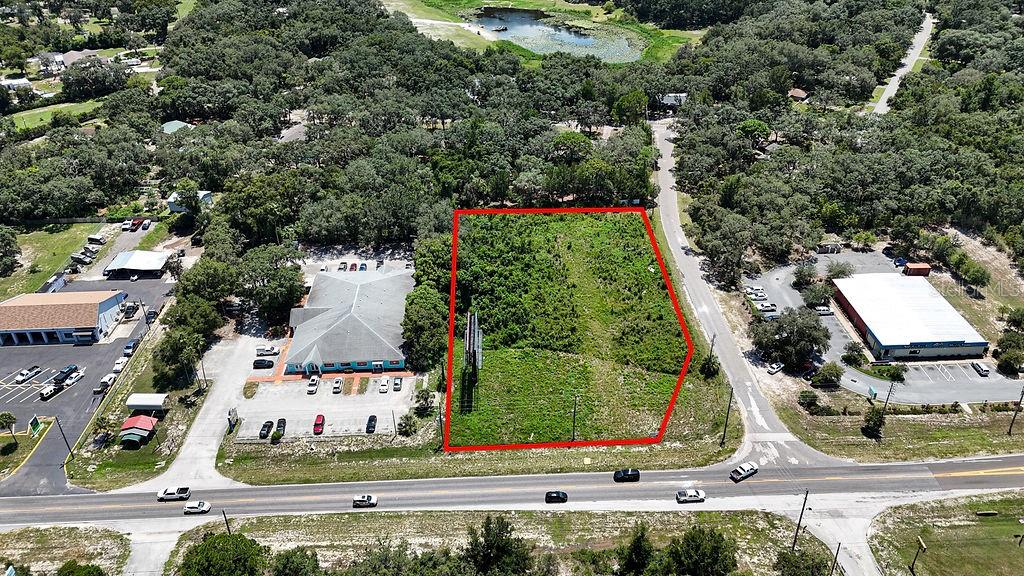 An aerial view shows a vacant, rectangular lot outlined in red beside commercial buildings — 18888 ACKSON STREET, SPRING HILL, FL