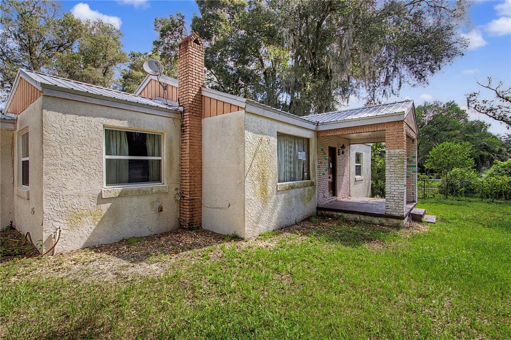 A single-story stucco house with a brick chimney and a covered front porch — 20179 THE GRANADA, DUNNELLON, FL