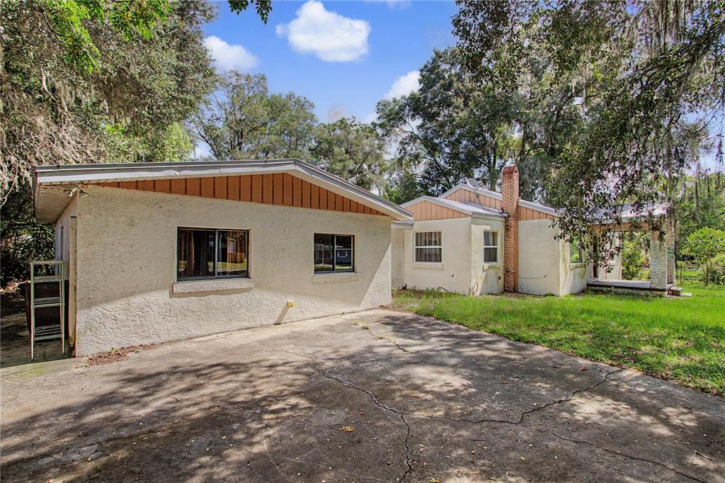 A view of the exterior of a single-story house with a concrete driveway and trees — 20179 THE GRANADA, DUNNELLON, FL