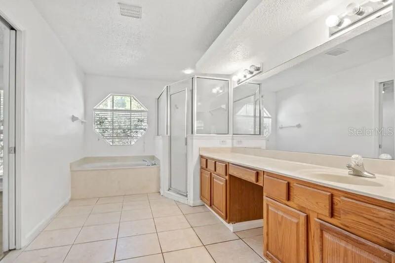 A bathroom features a soaking tub, a glass shower, and a wooden vanity with mirrors — 2429 W CEDAR TRACE DRIVE, JACKSONVILLE, FL