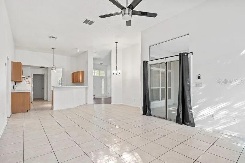 An open-concept living and dining area features white tile flooring, a ceiling fan, and sliding doors — 2429 W CEDAR TRACE DRIVE, JACKSONVILLE, FL