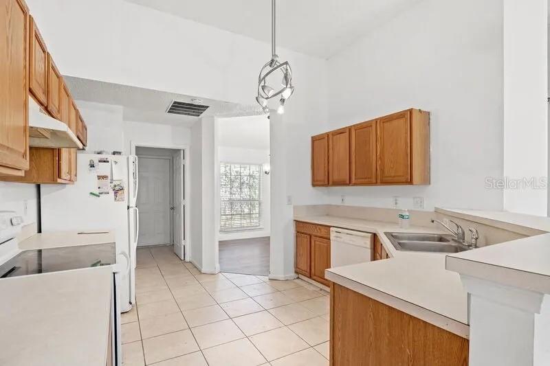 A kitchen features light-colored countertops, wood cabinets, tile flooring, and a white refrigerator — 2429 W CEDAR TRACE DRIVE, JACKSONVILLE, FL