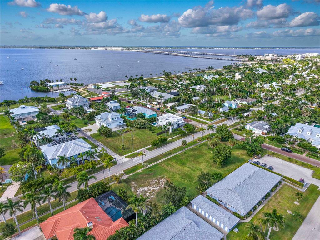 An aerial view shows a coastal neighborhood with houses, palm trees, and a long bridge — 817 W MARION AVENUE, PUNTA GORDA, FL