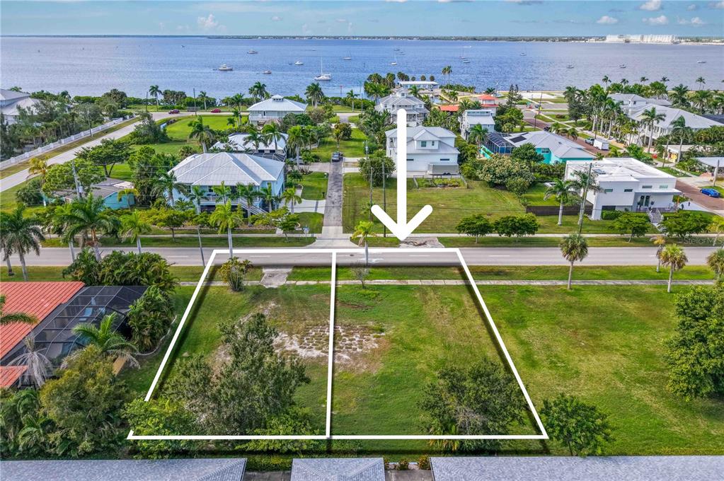 An aerial view shows two adjacent vacant lots of land near a body of water — 817 W MARION AVENUE, PUNTA GORDA, FL