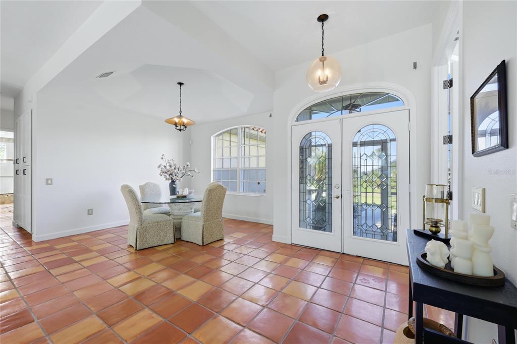 A bright foyer and dining area with terracotta tile floors and double glass entry doors — 4658 ARLINGTON DRIVE, PLACIDA, FL