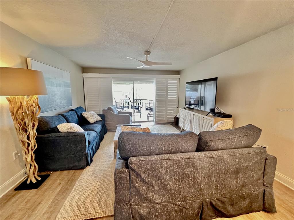 A living room features blue sofas, a wooden coffee table, and a television on a cabinet — 2100 N PENINSULA AVENUE UNIT 216, NEW SMYRNA BEACH, FL