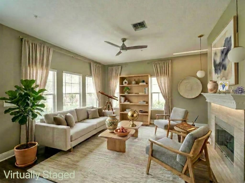 This virtually staged living room features a fireplace, neutral furniture, and a ceiling fan — 7174 REGINA WAY, ORLANDO, FL