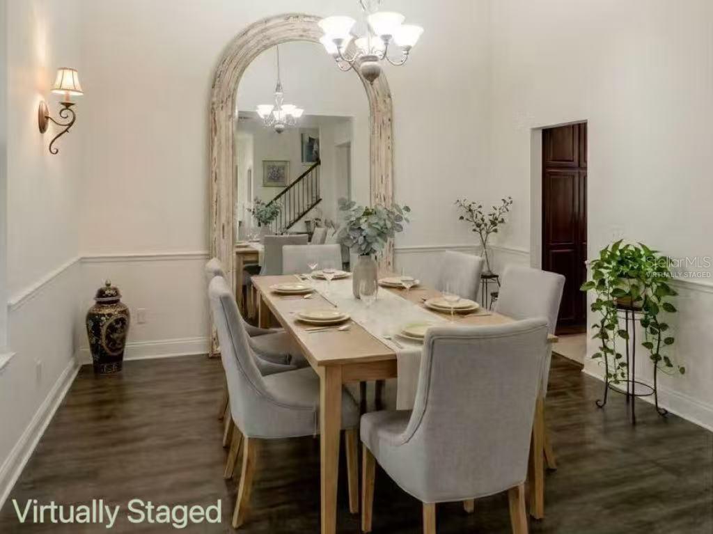 A dining room features a large arched mirror, a wooden table, and light gray chairs — 7174 REGINA WAY, ORLANDO, FL