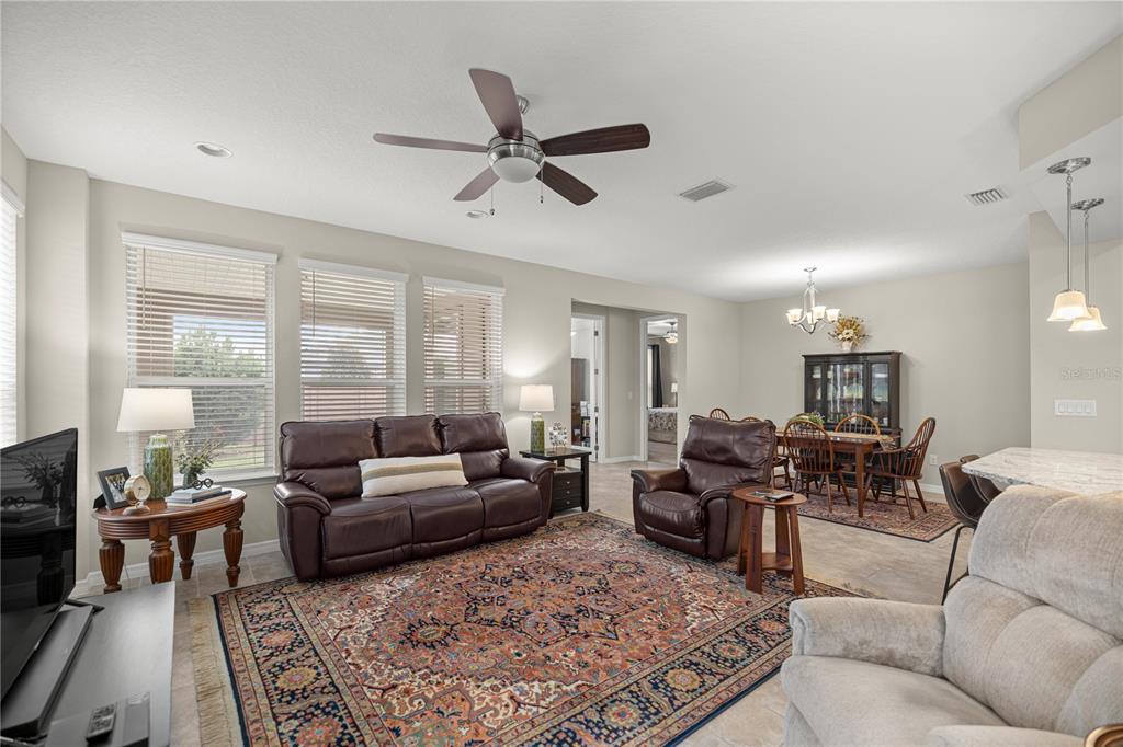 A living room with a brown leather sofa, patterned area rug, and adjacent dining area — 5504 NW 40TH LOOP, OCALA, FL