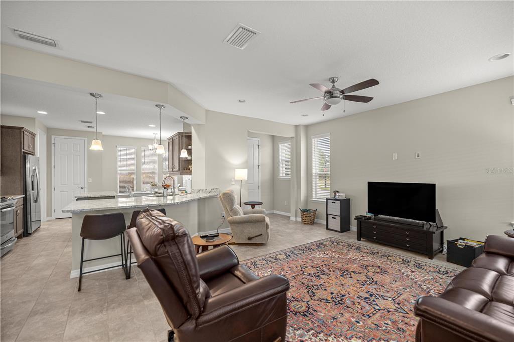 A living room with tile flooring, a patterned area rug, and an open-concept kitchen — 5504 NW 40TH LOOP, OCALA, FL