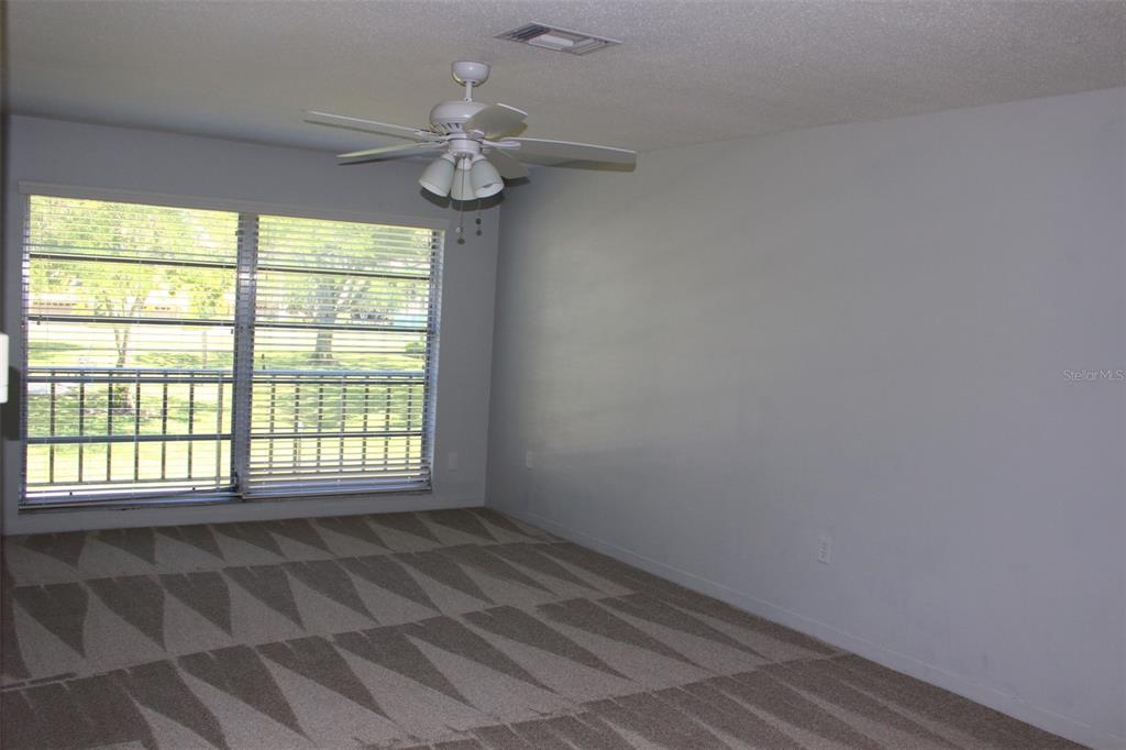An empty bedroom features gray walls, patterned carpet, and a ceiling fan with light fixtures — 2700 BAYSHORE BOULEVARD UNIT 2207, DUNEDIN, FL