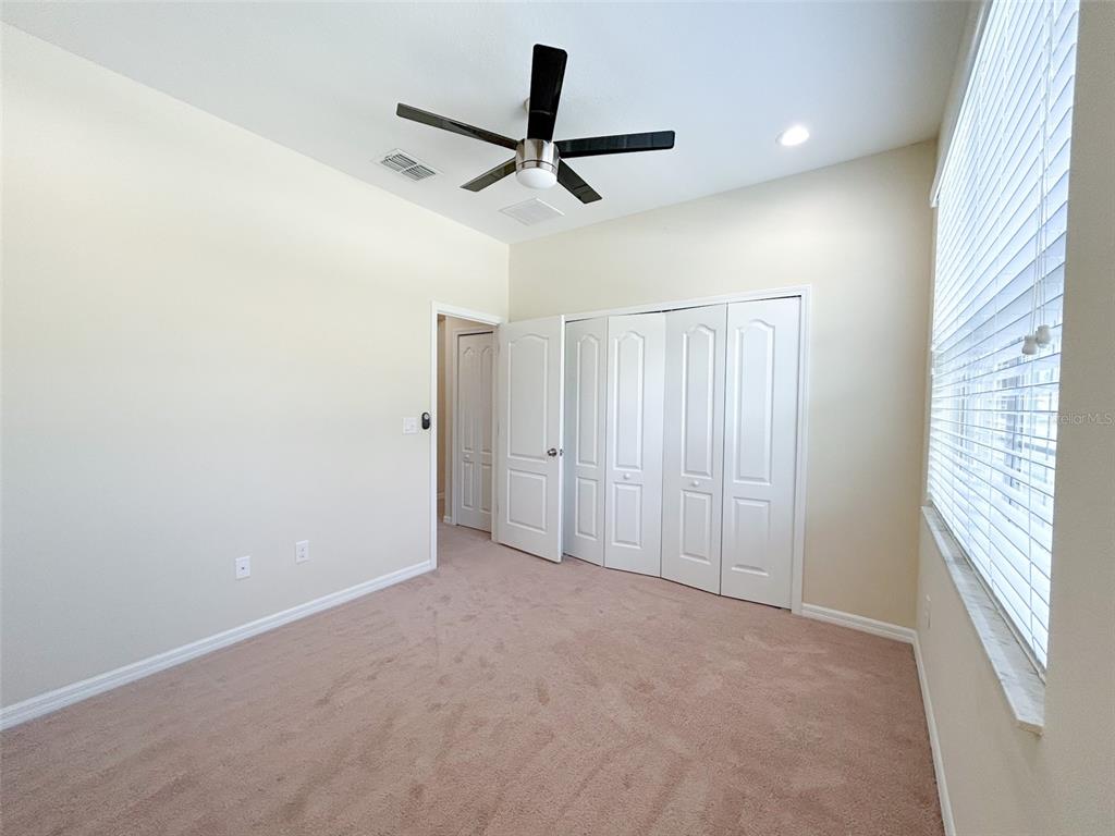 An empty bedroom features beige carpet, white walls, a ceiling fan, and a closet — 13814 BEE TREE COURT, HUDSON, FL