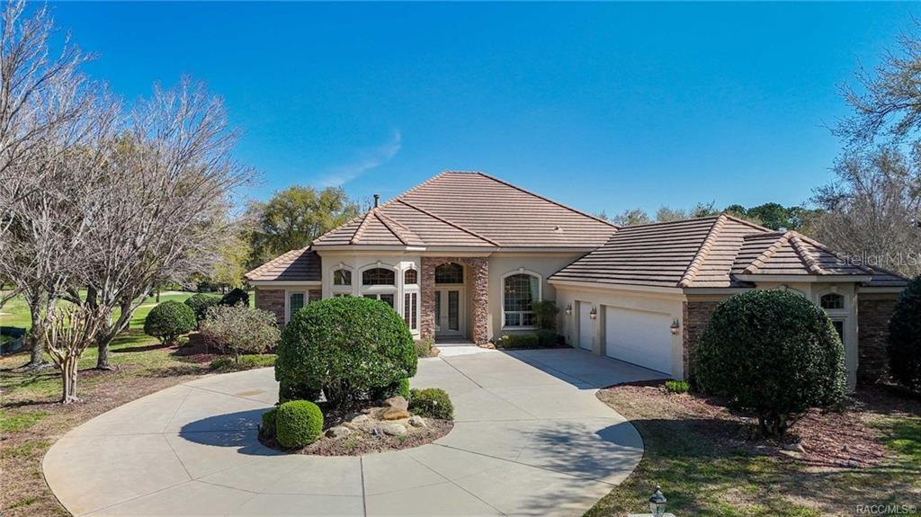 A single-story house with a tile roof, stone accents, and a circular concrete driveway — 3207 W WENTWORTH LOOP, LECANTO, FL
