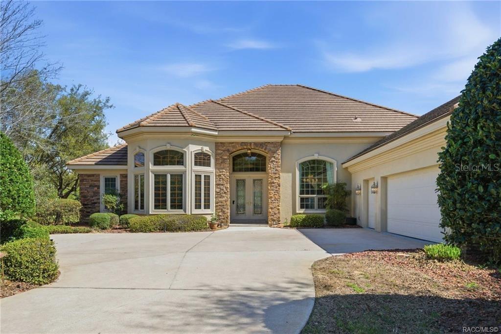 A single-story house with a stone facade, arched entryway, and a concrete driveway — 3207 W WENTWORTH LOOP, LECANTO, FL