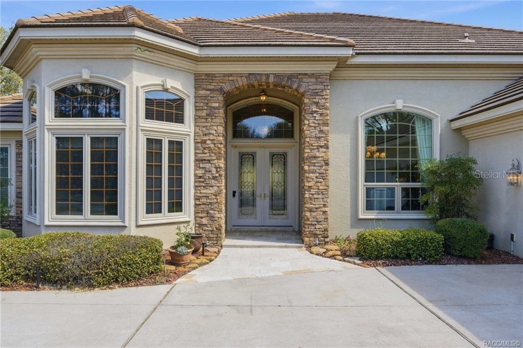 The exterior of a house features a stone-accented entryway with double glass doors — 3207 W WENTWORTH LOOP, LECANTO, FL