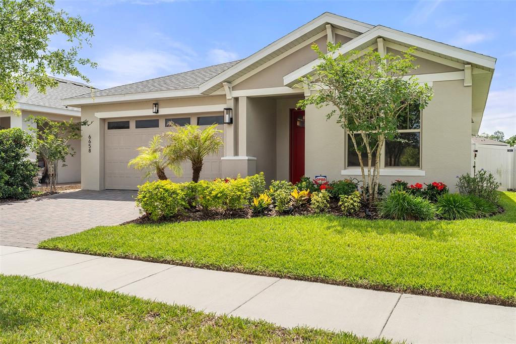 A single-story suburban house with a beige exterior, a red front door, and a paved driveway — 6658 SYREETA LANE, ST CLOUD, FL